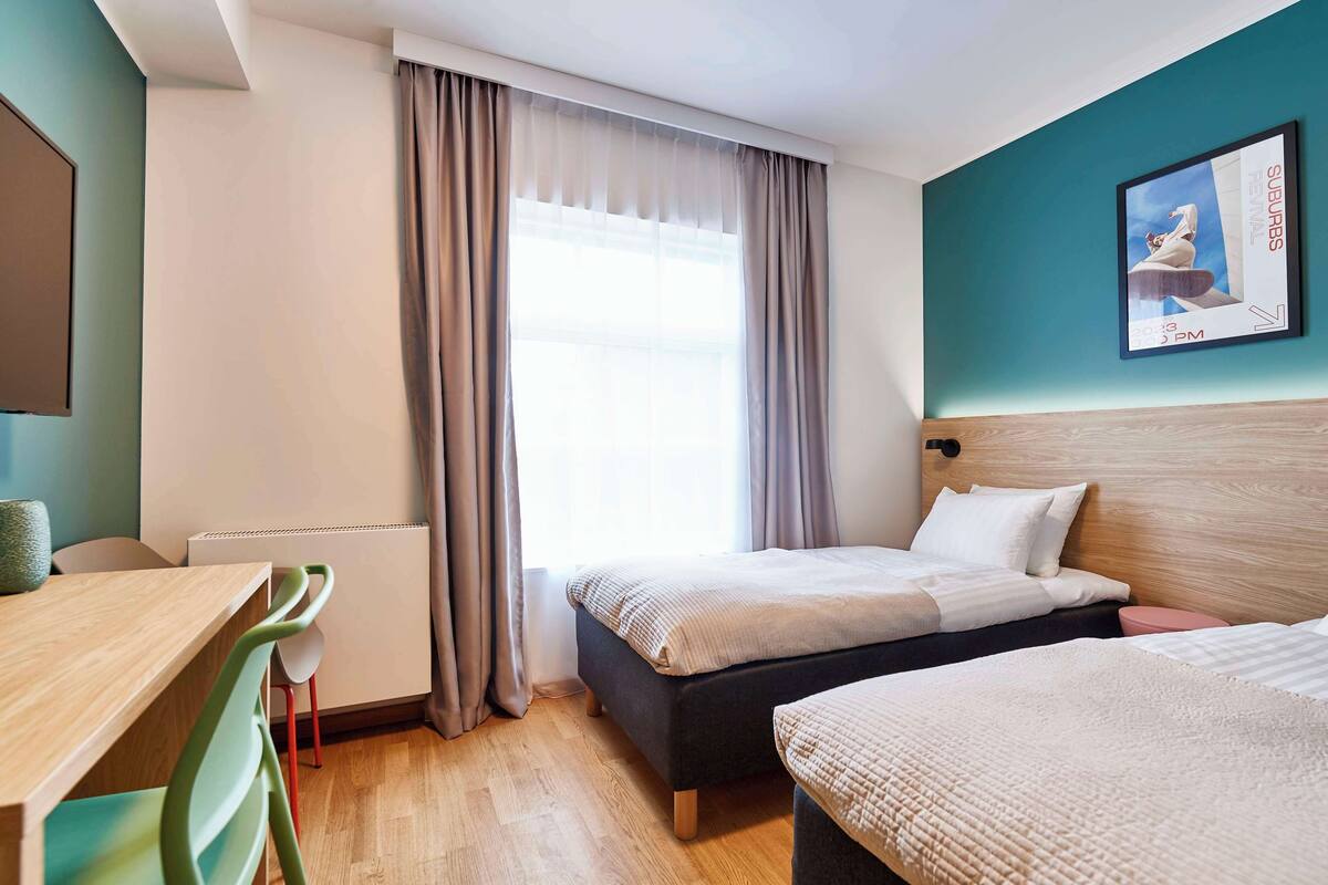 Hotellihuone, jossa on sänky, työpöytä ja tuoli.