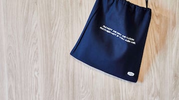 A navy blue drawstring bag with text on it, hanging on a wooden surface.