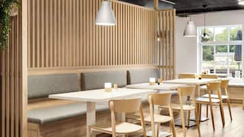 A modern restaurant with wooden panel walls, grey cushioned seating, and white tables.