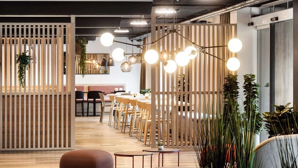 A modern interior with wooden partitions, round tables, and hanging spherical lights. - Aiden by Best Western Lolland (Holeby)