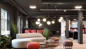 A modern office space with a large beige sofa, red and brown ottomans, and a central table. - Aiden by Best Western Lolland (Holeby)