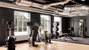 A gym with exercise equipment, large windows, and a mirrored wall. - Aiden by Best Western Lolland (Holeby)
