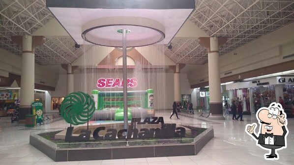 A shopping plaza with a central fountain, a Sears store, and a cartoon character. - Hotel del Norte (Mexicali)