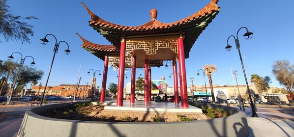 A traditional Chinese pavilion with red pillars and a tiled roof, surrounded by a landscaped area with a circular walkway. - Hotel del Norte (Mexicali)