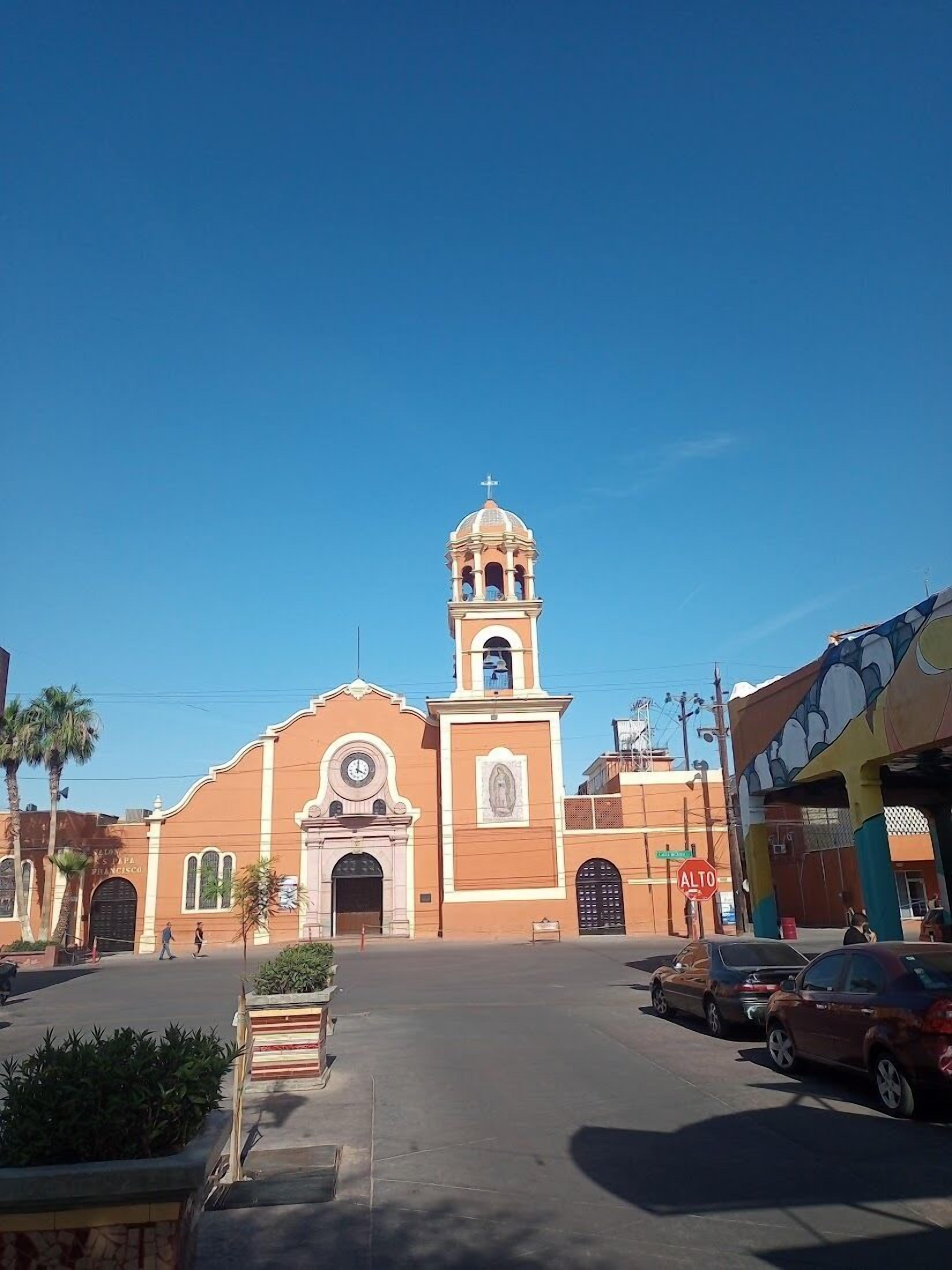 A church with a bell tower, a clock, and a sign reading "PAPAS FRANCISCO".
