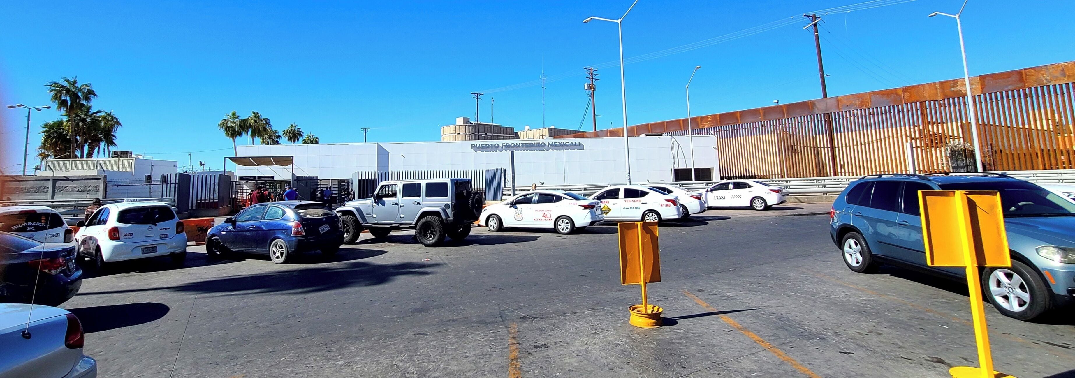 Un estacionamiento con varios coches, incluyendo una furgoneta blanca y un SUV azul.