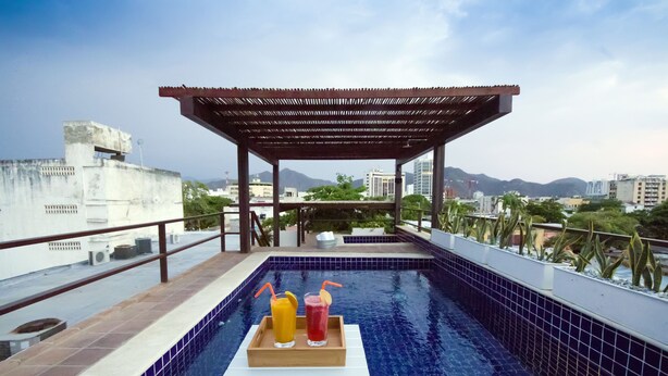 A rooftop pool with a wooden pergola, a table with two drinks, and a cityscape view. - La Casa Del Piano Hotel Boutique by Xarm Hotels (Santa Marta)