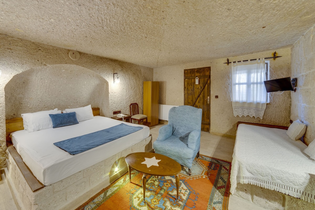 A room with a bed, a chair, a small table, and a sofa.
