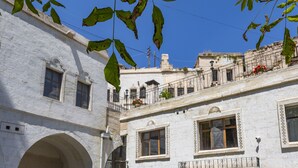 Un patio con edificios blancos, arcos y balcones con barandillas.