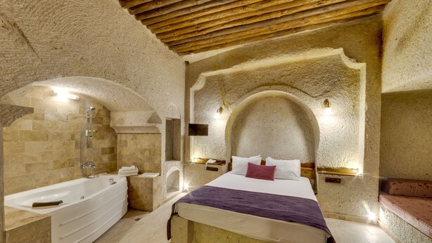 Un dormitorio con una cama grande, una bañera y paredes de piedra.