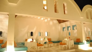 A dining area with white tables and chairs, blue cushioned seating, and a white interior. - Thalassa Sousse Resort & Aquapark (Sousse)