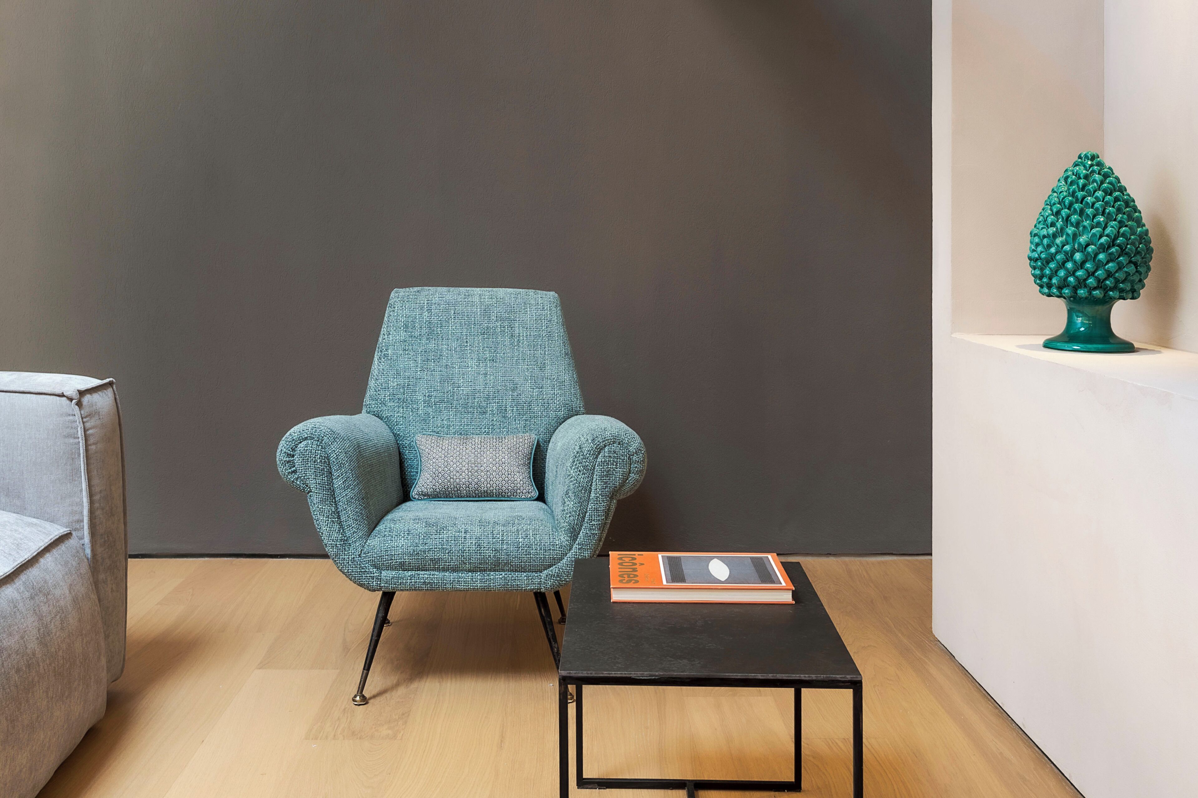 A room with a teal armchair, a small table, and a decorative tree sculpture.