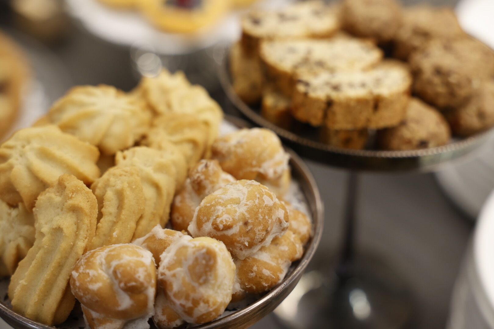 A variety of pastries in a metal dish, including puff pastries and cream-filled pastries.