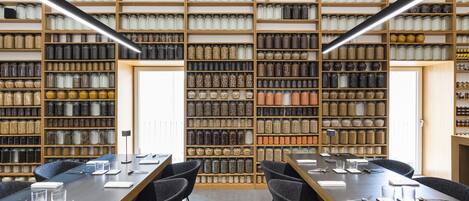 A conference room with a long table, chairs, and a wall of storage jars.