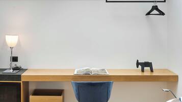 A modern workspace with a wooden desk, a blue chair, a lamp, and a book.