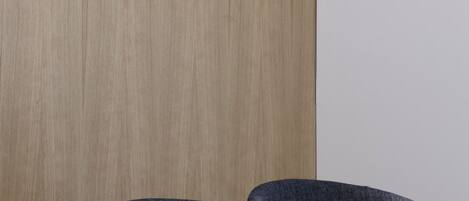 Una habitación moderna con un separador de madera, tres lámparas colgantes negras y una fila de sillas tapizadas en gris oscuro.