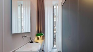 Un bagno moderno con un lavandino bianco grande, uno specchio e una luce verde.