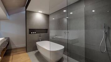 Un bagno moderno con una vasca freestanding, un box doccia in vetro e un mobile lavabo con specchio.