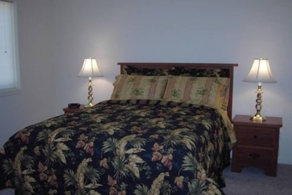 A bed with a floral bedspread, two bedside lamps, and a wooden headboard.