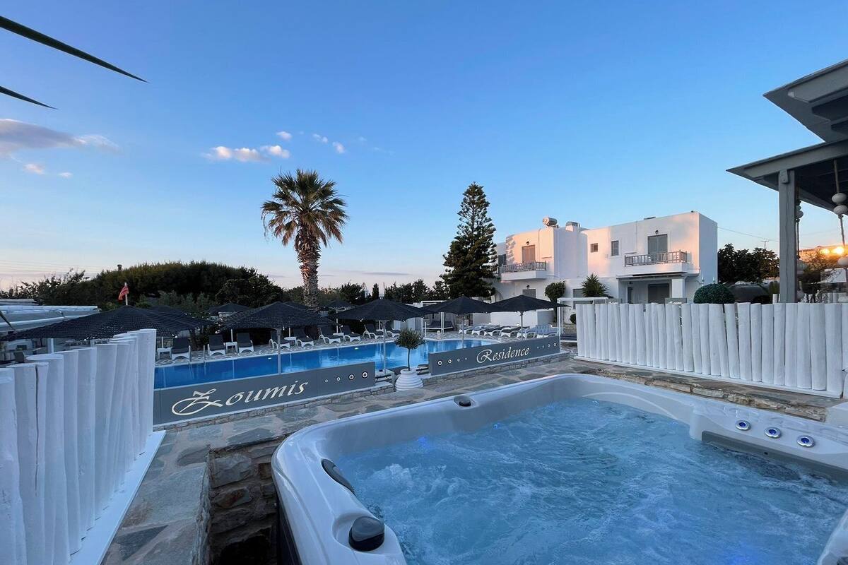 A hot tub area with a pool, lounge chairs, umbrellas, and a sign that reads "Residence".