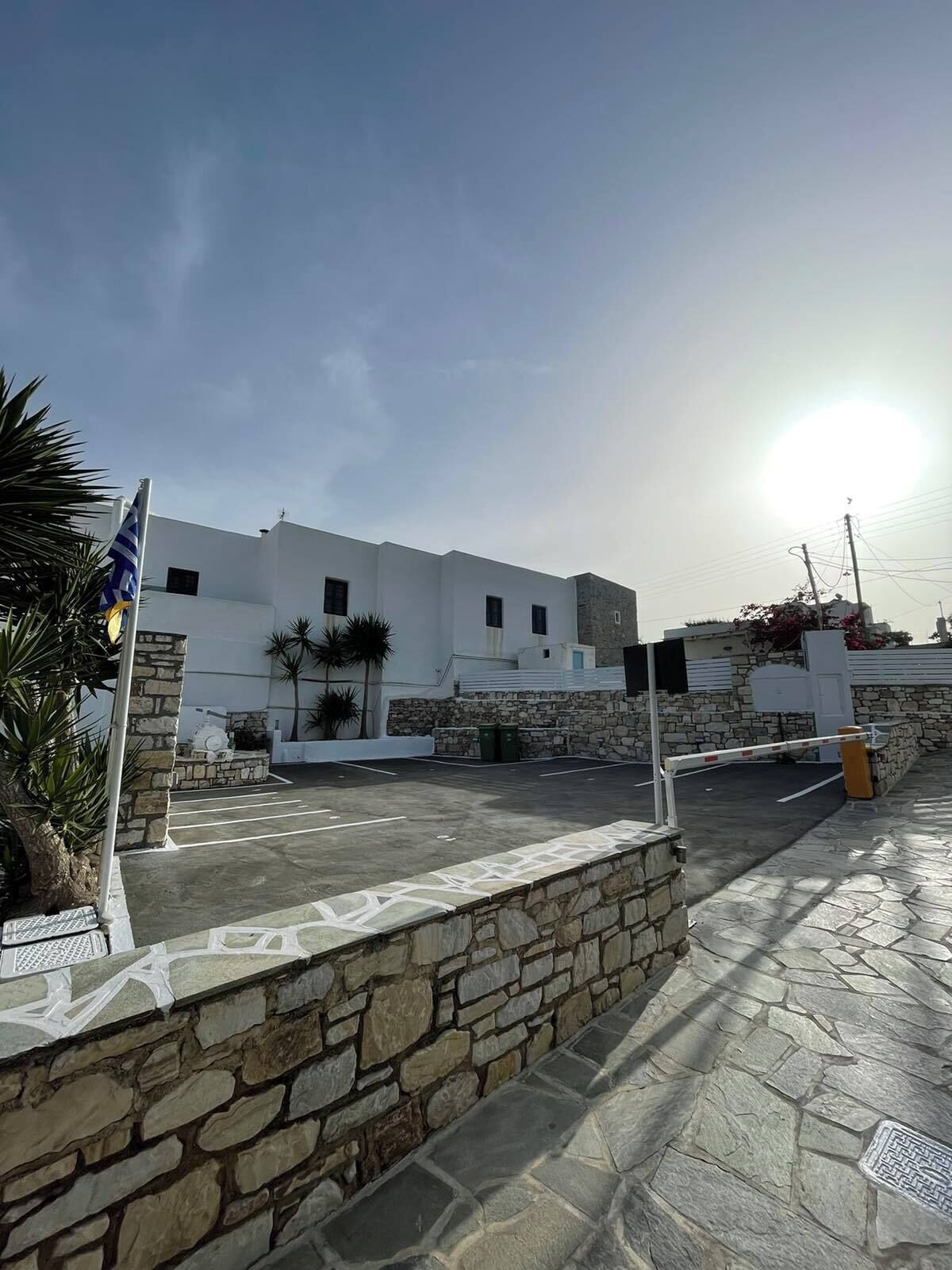 A white building with stone walls and a paved area in front.