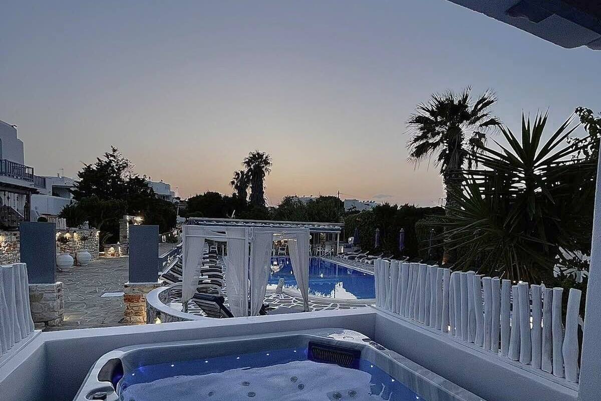 A hot tub with a view of a pool and palm trees.
