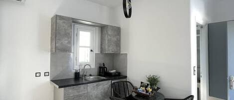 A modern kitchen with grey cabinetry, a window, and a dining area with wicker chairs.