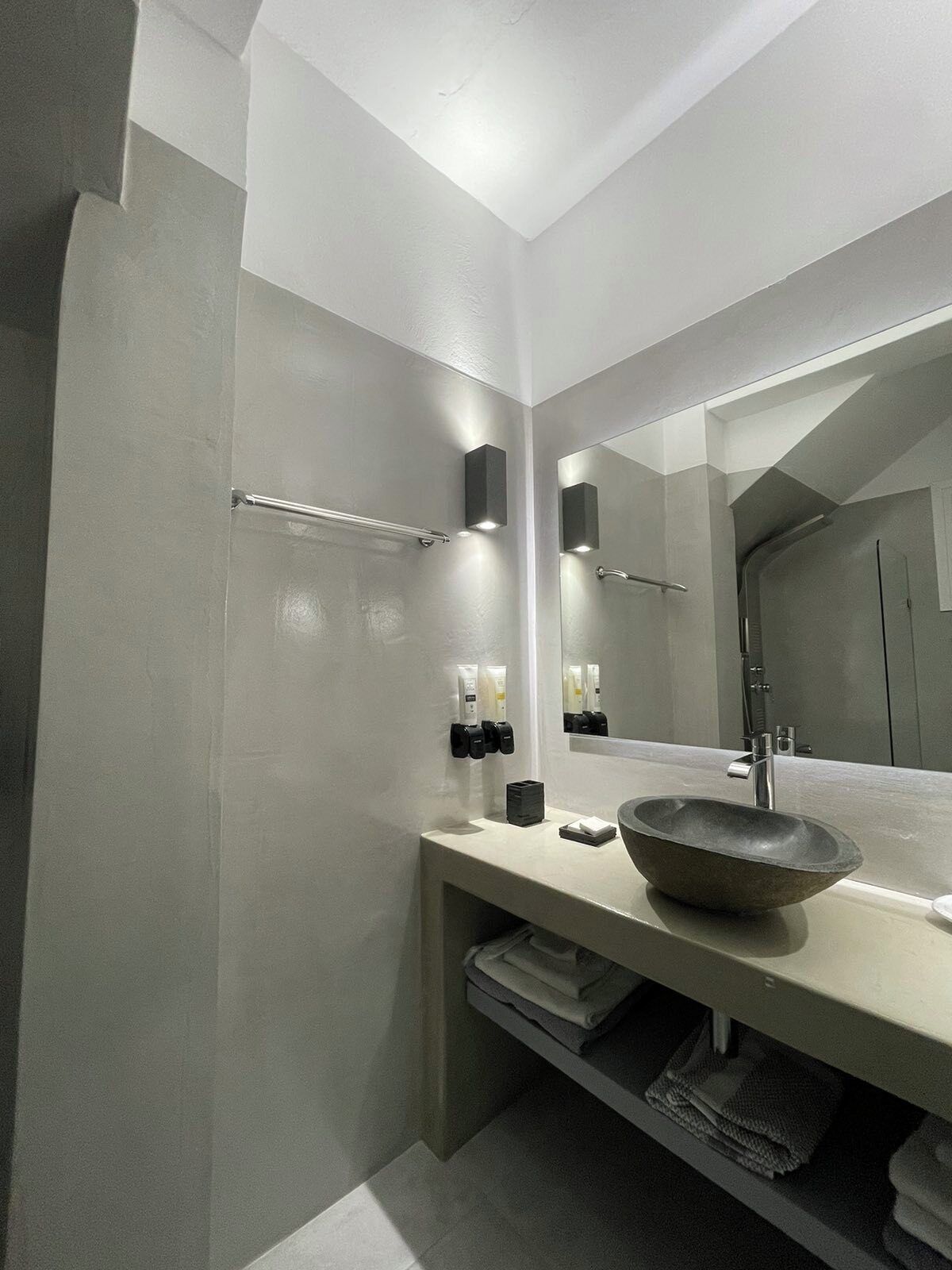 A modern bathroom with a large mirror, a vessel sink, and towel racks.