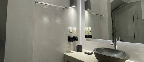 A modern bathroom with a large mirror, a vessel sink, and towel racks.