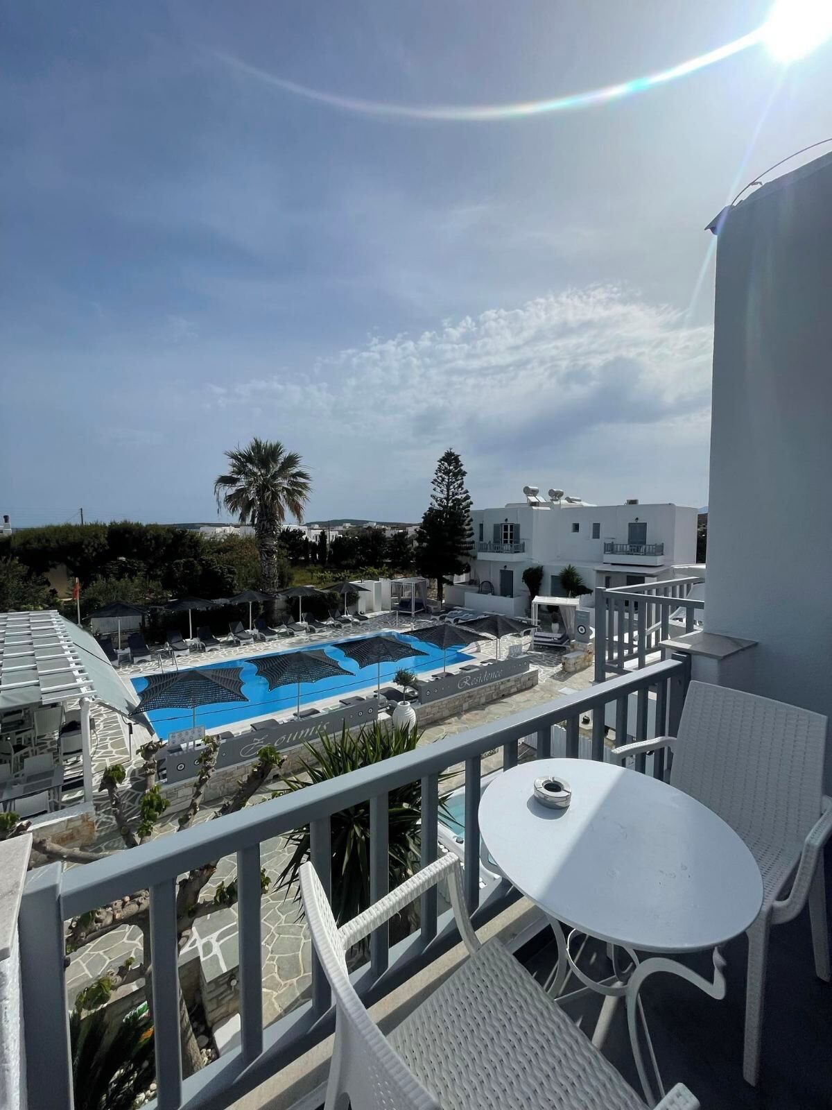 A balcony with a pool, white furniture, and a view of the surrounding buildings.