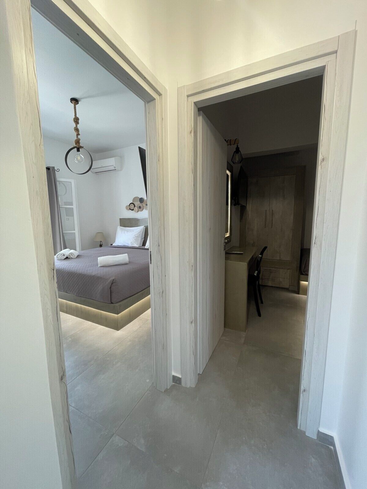 A modern bedroom with a bed, bedside table, and a hanging light fixture.