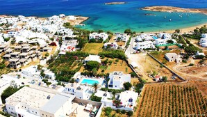 An aerial view of a coastal town with white buildings, a clear blue sea, and a small island in the distance.