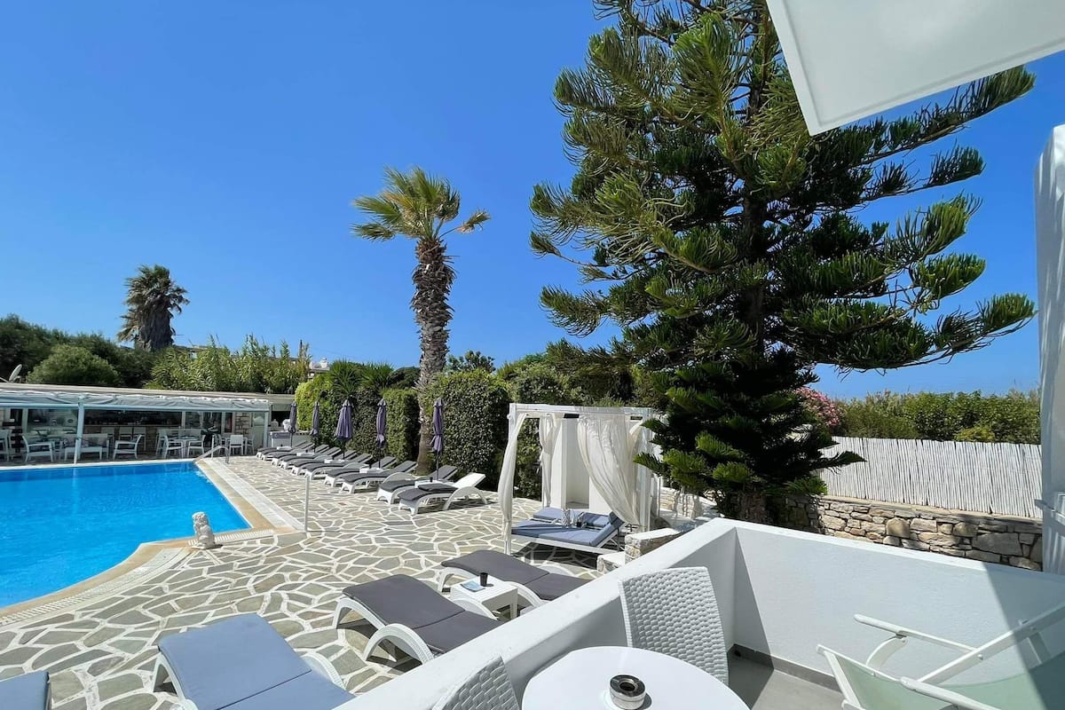 A poolside area with lounge chairs, a table, and a pergola.