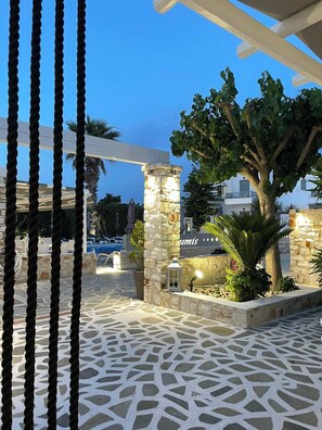 A stone pillar with a sign, a patterned floor, and a tree in a courtyard.