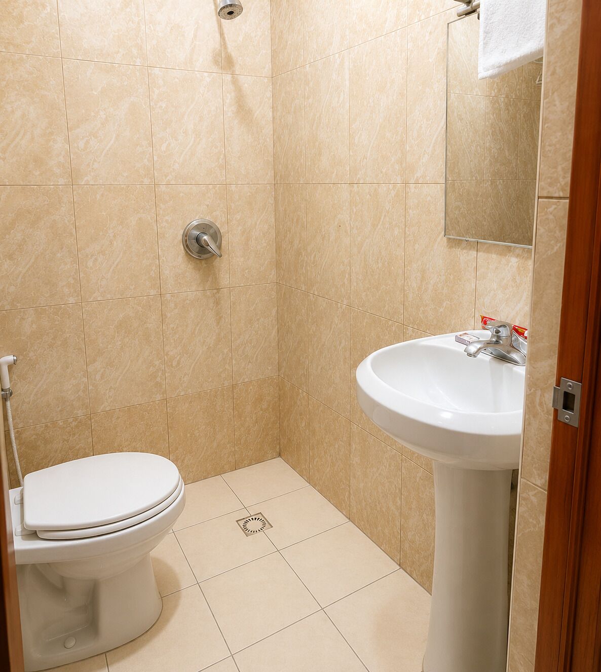 A small, tiled bathroom with a toilet, a sink, and a shower.