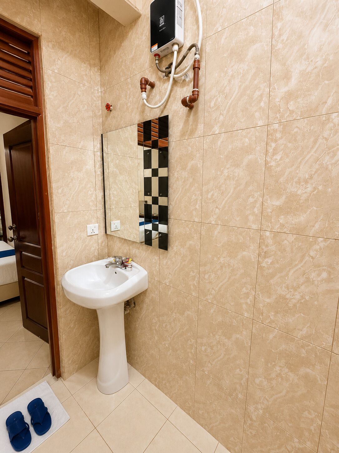 Een badkamer met een witte wastafel, een spiegel met een geruit frame en een handdoekhouder.