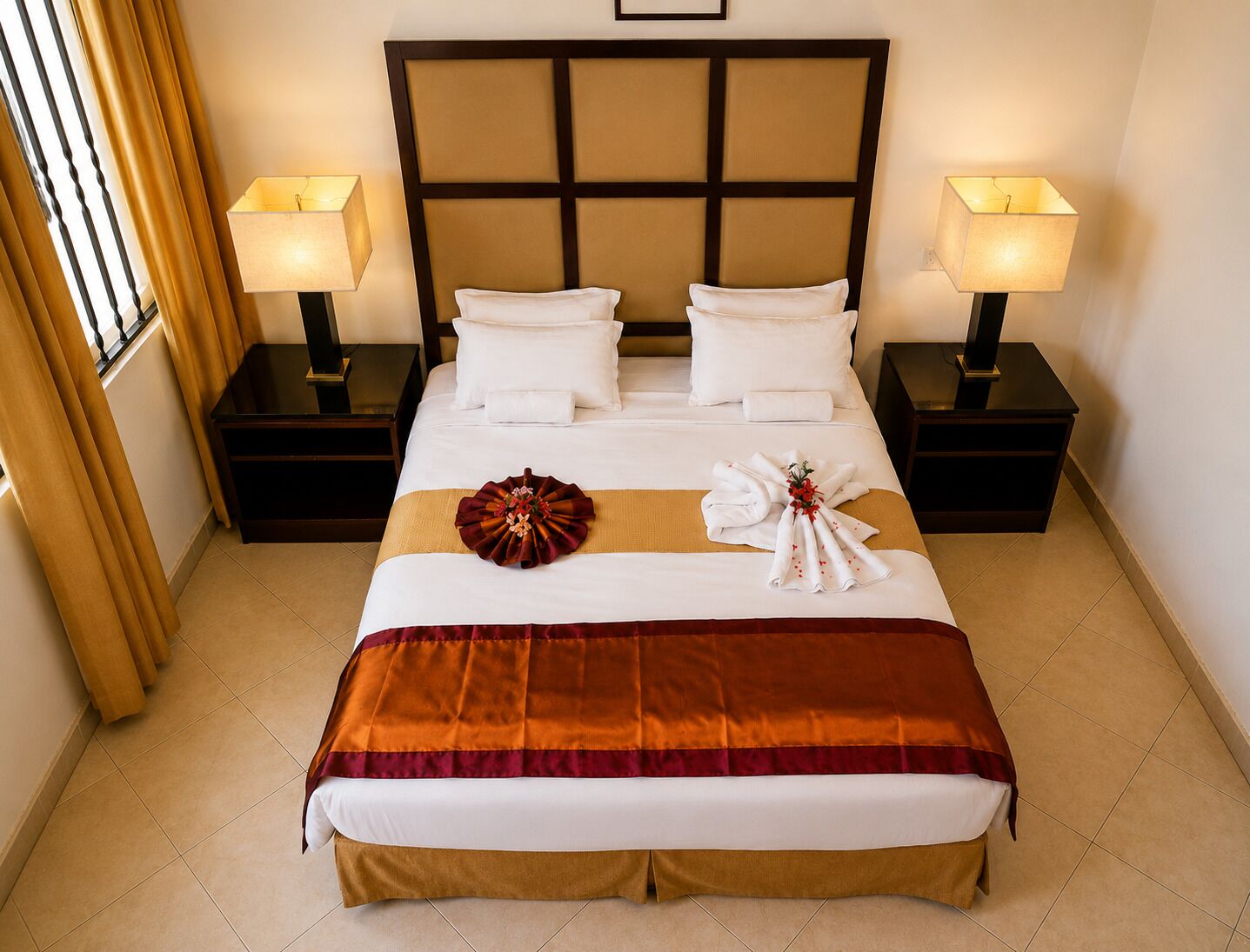 A hotel room with a large bed, two bedside tables, and two lamps.