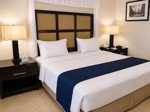 Habitación de hotel con una cama, dos mesitas de noche, una lámpara, un teléfono y un cuadro en la pared.