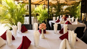 Una mesa lista para comer con servilletas blancas, copas transparentes y un florero con flores.