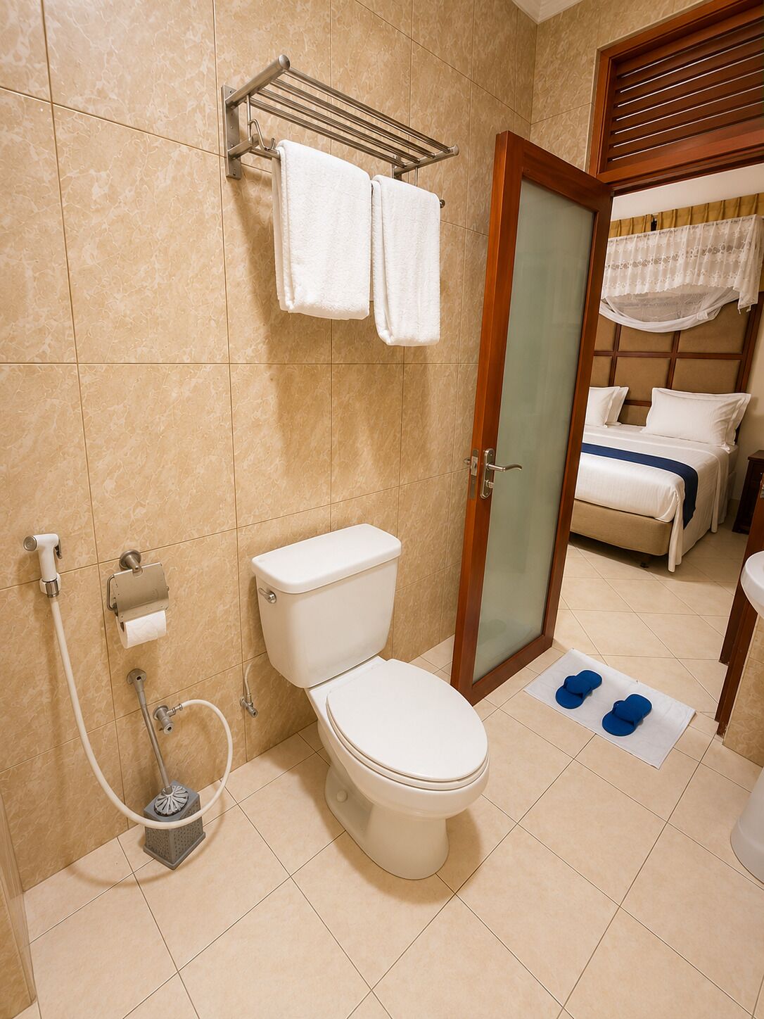 Un baño con inodoro, toallero, ducha y cama con dosel.