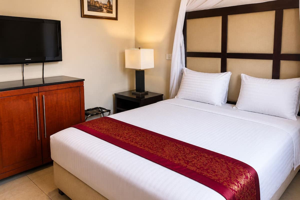 A hotel room with a bed, a television, a nightstand, a lamp, and a wardrobe.
