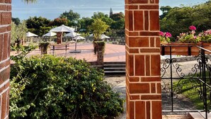 Estructura de ladrillo con vista a un área ajardinada, que incluye una piscina y sombrillas.