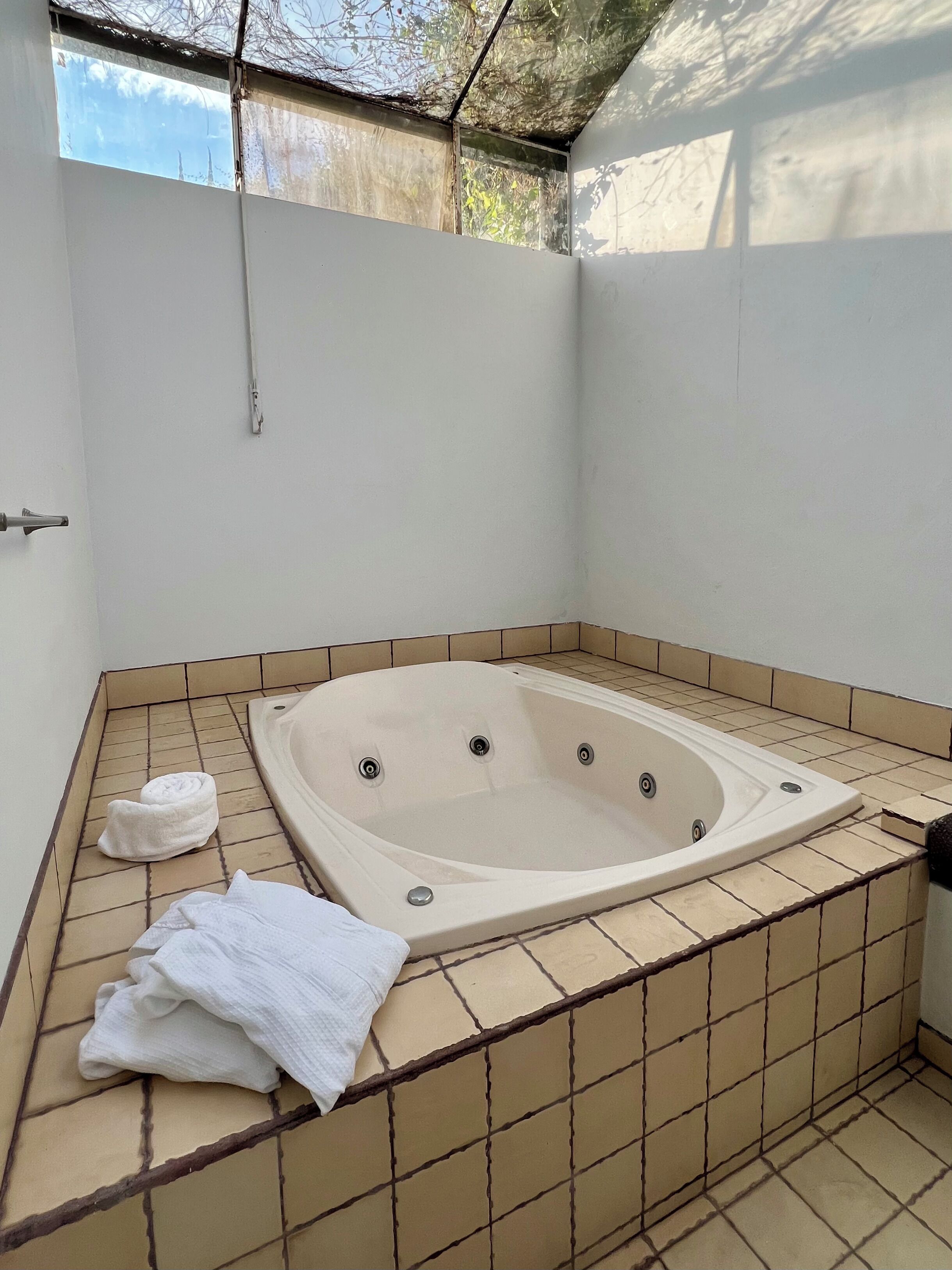 A bathroom with a freestanding bathtub, tiled walls, and a window providing natural light.