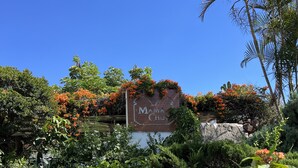 Ein Schild mit der Aufschrift "Mama Chuy", umgeben von üppigem Grün und blühenden Pflanzen.