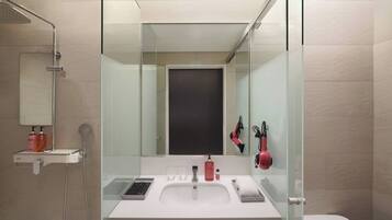 Une salle de bain moderne avec une douche à l’italienne en verre, un lavabo blanc et un grand miroir.