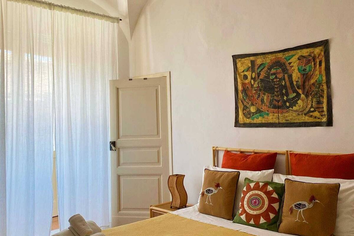 Habitación de hotel con cama, almohadas, un cuadro y una puerta.