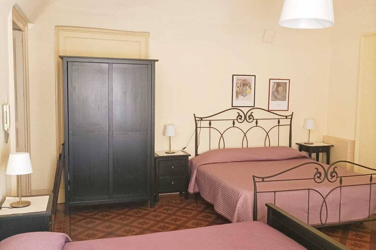 Un dormitorio con dos camas, un armario y una lámpara colgante.