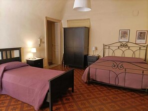 Ein Zimmer mit zwei Betten, einem Schrank, einer Tür und einer Wand mit gerahmten Bildern.