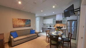 A modern apartment with a living room, dining area, kitchenette, and a flat-screen TV mounted on the wall. - Wasaga Riverdocks Hotel Suites (Wasaga Beach)