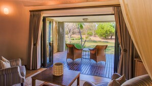 A room with a wooden deck, a table with chairs, and a view of the outdoors. - Lilayi Lodge (Lusaka)